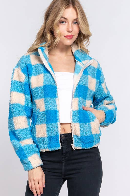 Woman wearing a blue and beige checkered fleece jacket on a white background