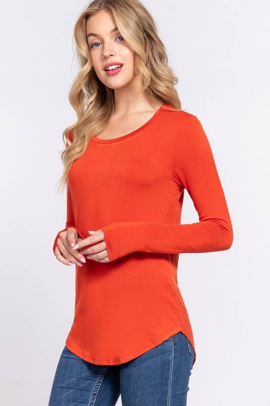 Woman wearing an orange long-sleeve top against a white background