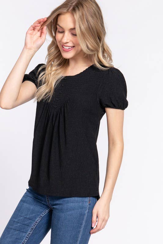 Woman wearing a black short-sleeve top and blue jeans on a white background